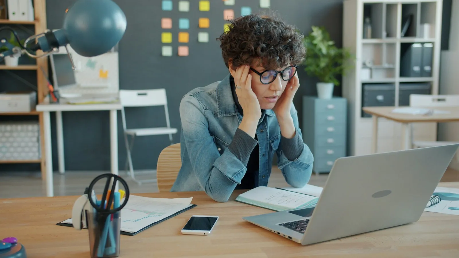 A person holding their head in front of a laptop